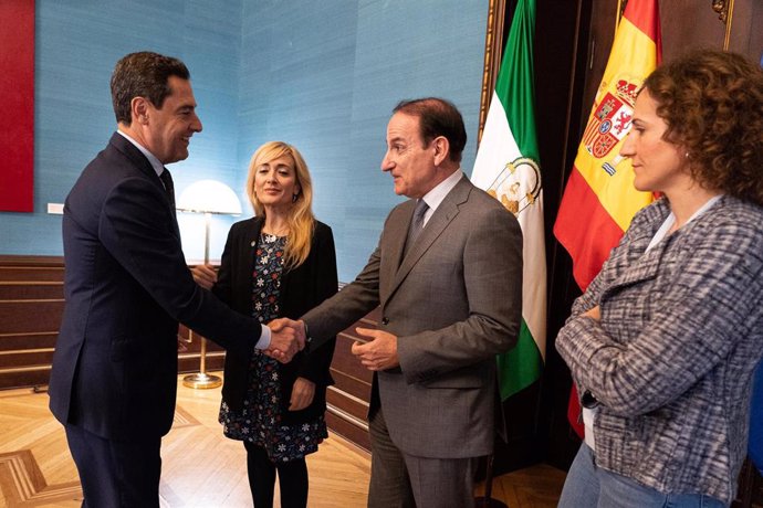 El presidente de la Junta de Andalucía, Juanma Moreno (1i) saluda al presidente de la CEA, Javier González de Lara (c), junto a la secretaria general de CCOO-A, Nuria López Marín (1d) y la secretaria general del UGT de Andalucía, Carmen Castilla