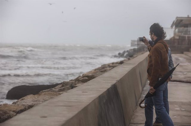 Archivo - Dos personas fotografían el mar, en la playa de la Malvarrosa
