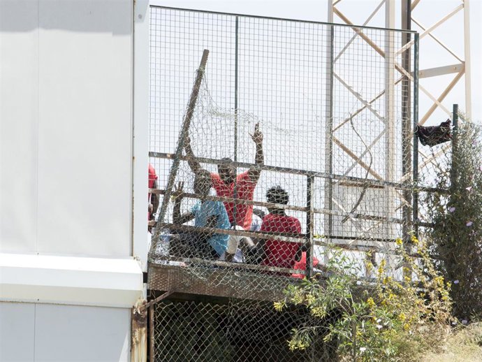 Archivo - Varios migrantes junto a la valla fronteriza de Melilla