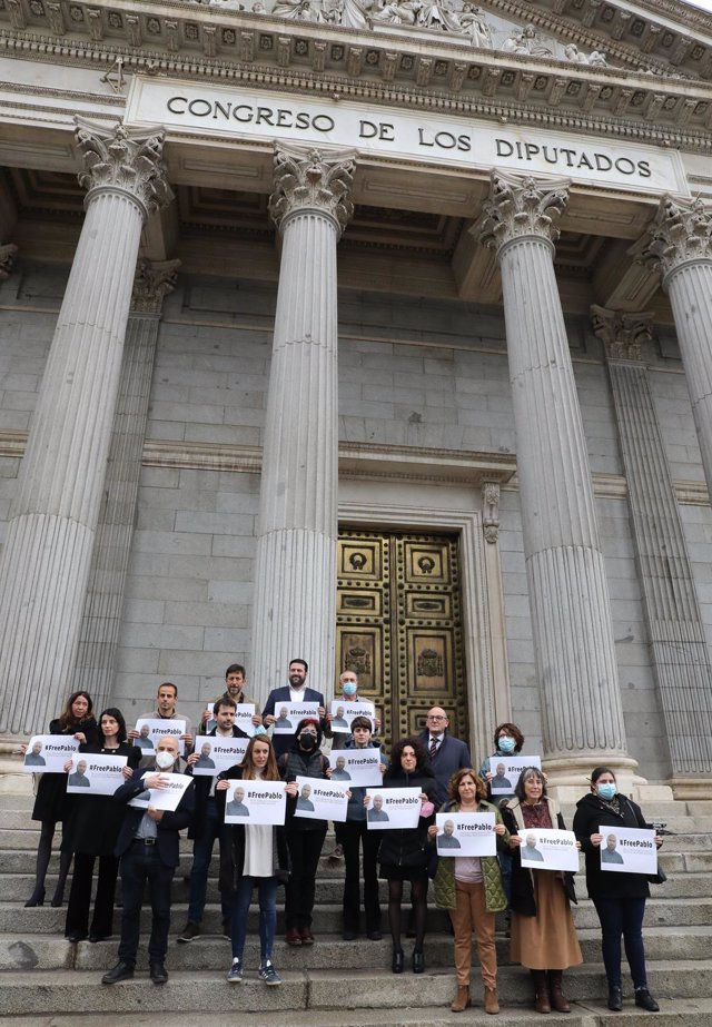 Diputados de Podemos portan carteles con imágenes del periodista Pablo González, detenido en Polonia mientras informaba sobre la guerra en Ucrania, frente al Congreso de los Diputados, a 30 de marzo de 2022, en Madrid (España)