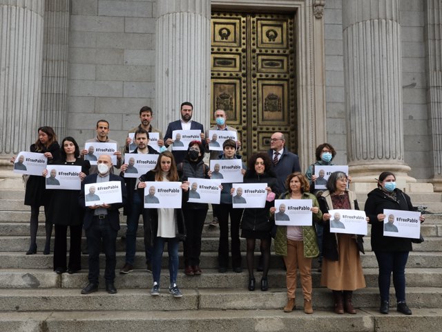 Diputados de Podemos portan carteles con imágenes del periodista Pablo González, detenido en Polonia mientras informaba sobre la guerra en Ucrania, frente al Congreso de los Diputados, a 30 de marzo de 2022, en Madrid (España)