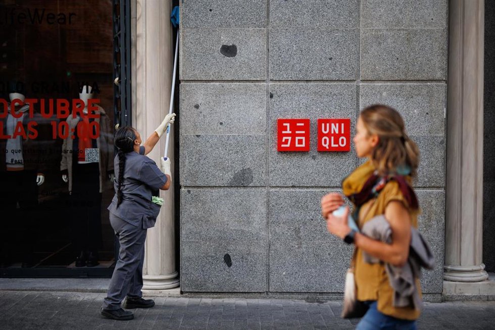 Archivo - Una empleada limpia la fachada de una tienda en Madrid.