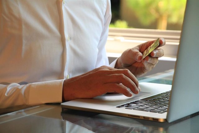 Recurso de comercio electrónico con una persona ante un ordenador portátil con la tarjeta bancaria para comprar