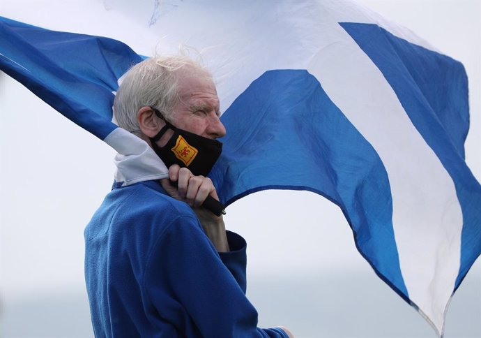 Archivo - Un hombre con mascarilla portando la bandera de Escocia durante una manifestación independentista