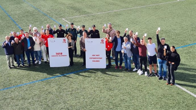 Miembros del Gover, FFIB y comités de árbitros y contra la violencia posan en un campo de fútbol mostrando la tarjeta blanca.