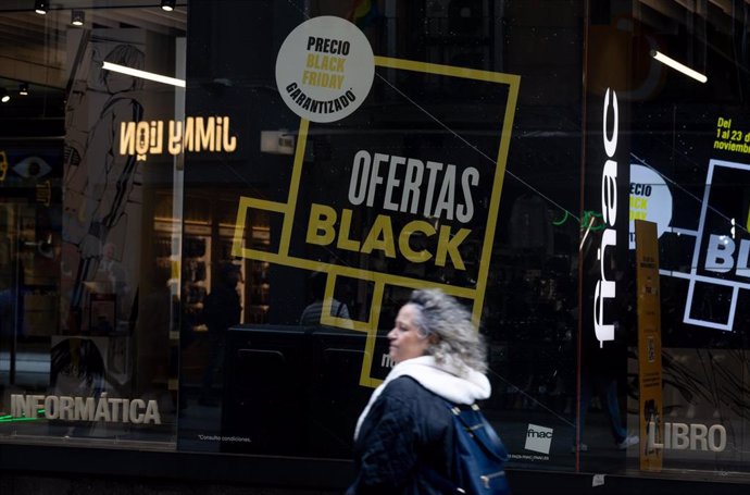 Una persona pasa por delante de una tienda que anuncia un cartel publicitario del Black Friday, 