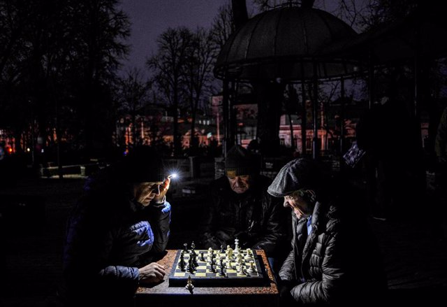 Varios hombres juegan al ajedrez durante un apagón en Kiev, Ucrania