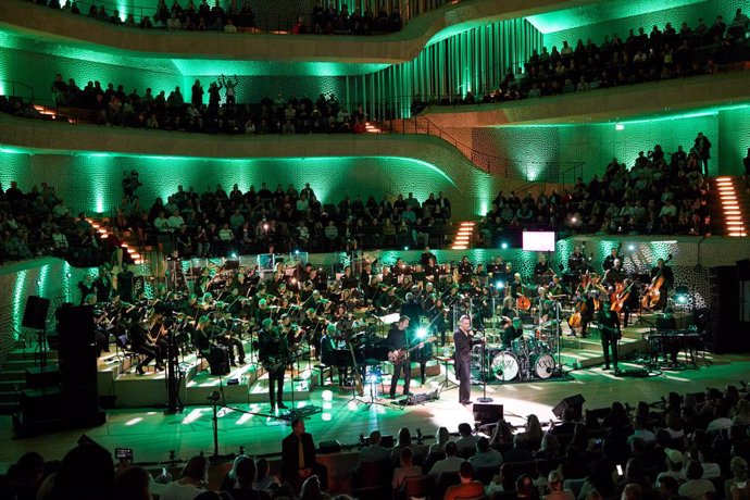 15 November 2022, Hamburg: British singer Robbie Williams and musicians of the New Philharmonic Orchestra Frankfurt perform on stage during a live concert in the Great Hall at the Elbphilharmonie. Williams gave a concert to celebrate 25 years of his sol