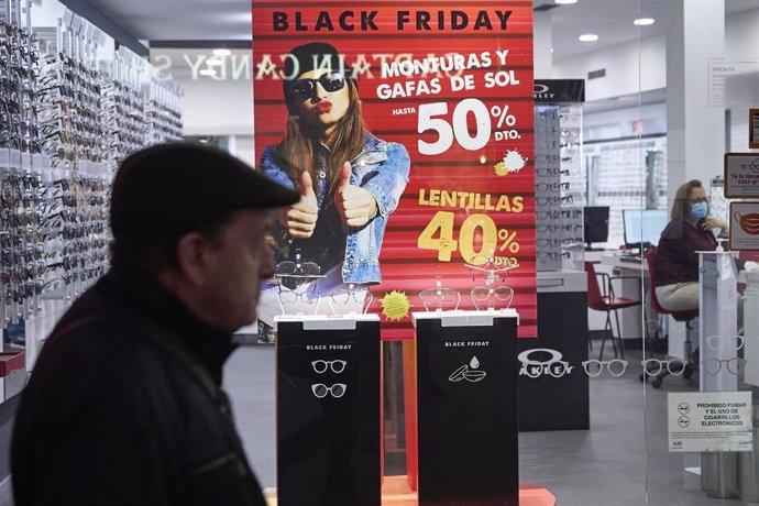 Varias personas pasan por delante de los comercios que anuncian los descuentos del Black Friday, 