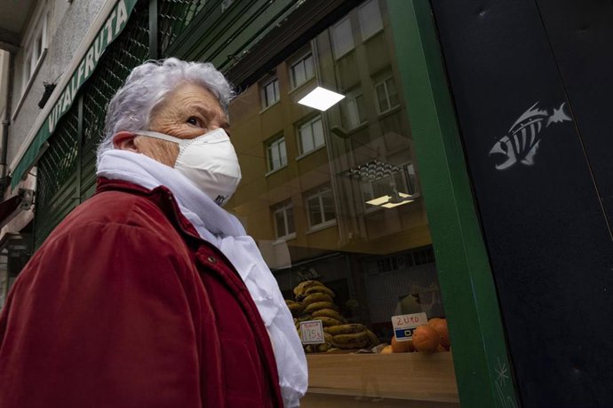 Archivo - Una mujer protegida con mascarilla se dirige a la entrada de un establecimiento alimenticio en A Coruña 