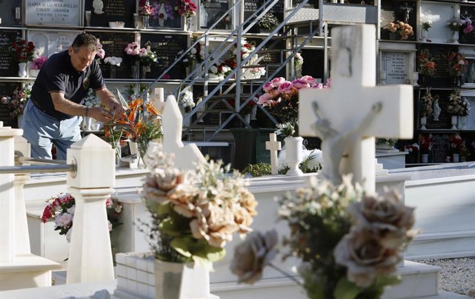 Un hombre colocando flores en la tumba de un ser querido, imagen de archivo
