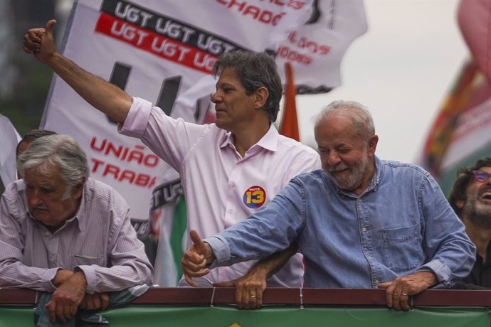 29 October 2022, Brazil, Sao Paulo: Brazilian former President and presidential candidate for the Workers' Party Lula da Silva (R) and PT candidate for Sao Paulo governor Fernando Haddad (L) wave to supporters alongside former Uruguayan President Pepe M
