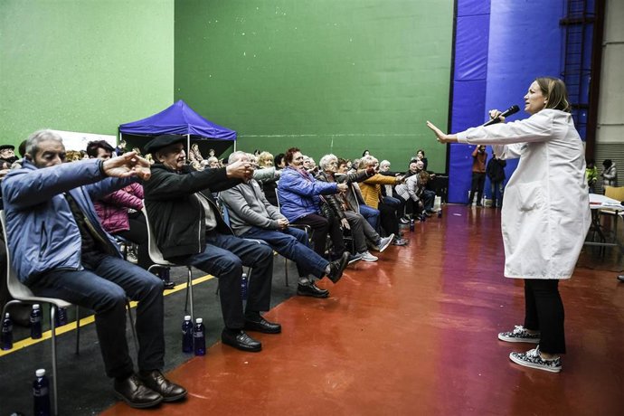 Una profesional de Geriatría de Navarrabiomed realiza ejercicios con el público asistente.
