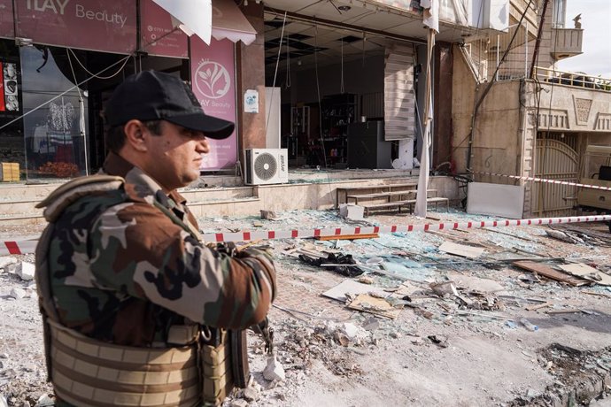 22 November 2022, Iraq, Duhok: AKurdish security personnels stands in front of a destroyed building following a gas tank explosion. At 4 people were killed and 26 people were injured after a gas tank exploded in a students' accommodation building. Phot
