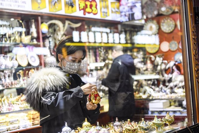 Archivo - Una mujer observa un producto en una tienda de Urumqi, Xinjiang