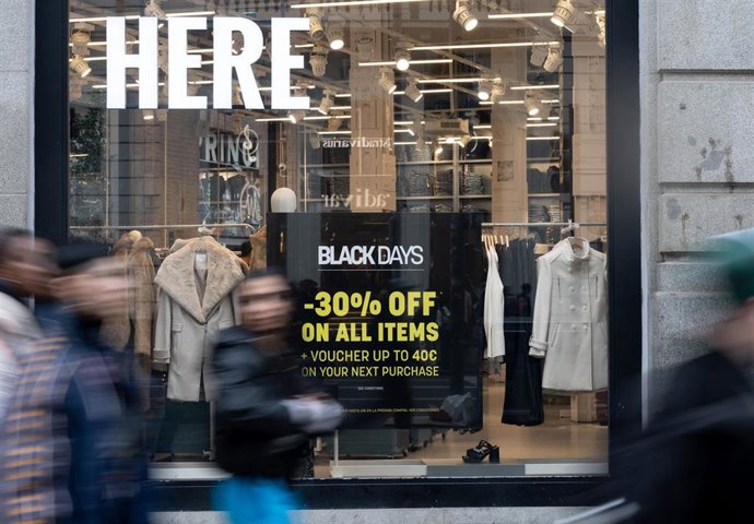 Varias personas pasan por delante de los comercios que anuncian los descuentos del Black Friday