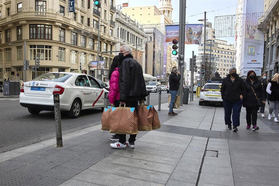 Archivo - Varias personas en la calle Gran Vía de Madrid con un taxi.