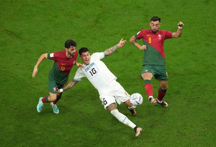 Bruno Fernandes  y Bernardo Silva pelean un balón con Mathias Olivera en el Portugal-Uruguay del Mundial de Catar