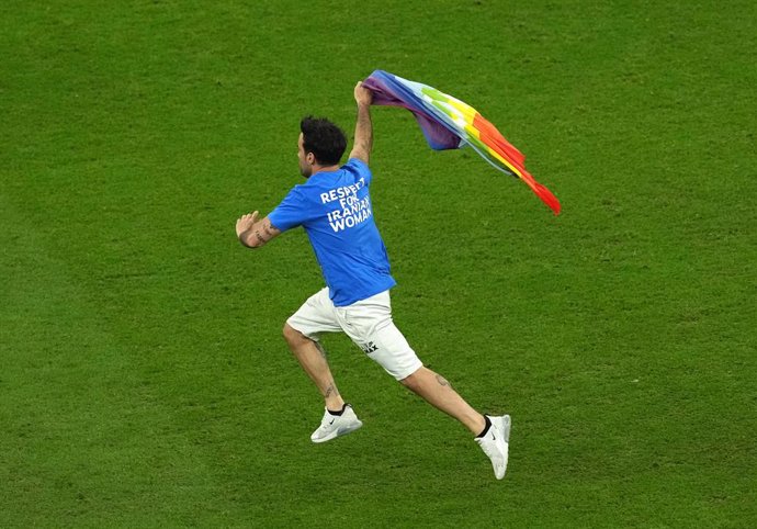 28 November 2022, Qatar, Lusail: A streaker with the rainbow flag and political messages about Ukraine and Iran on the T-shirt runs across the lawn during the FIFA World Cup Qatar 2022 Group H soccer match between Portugal and Uruguay at Lusail Stadium.