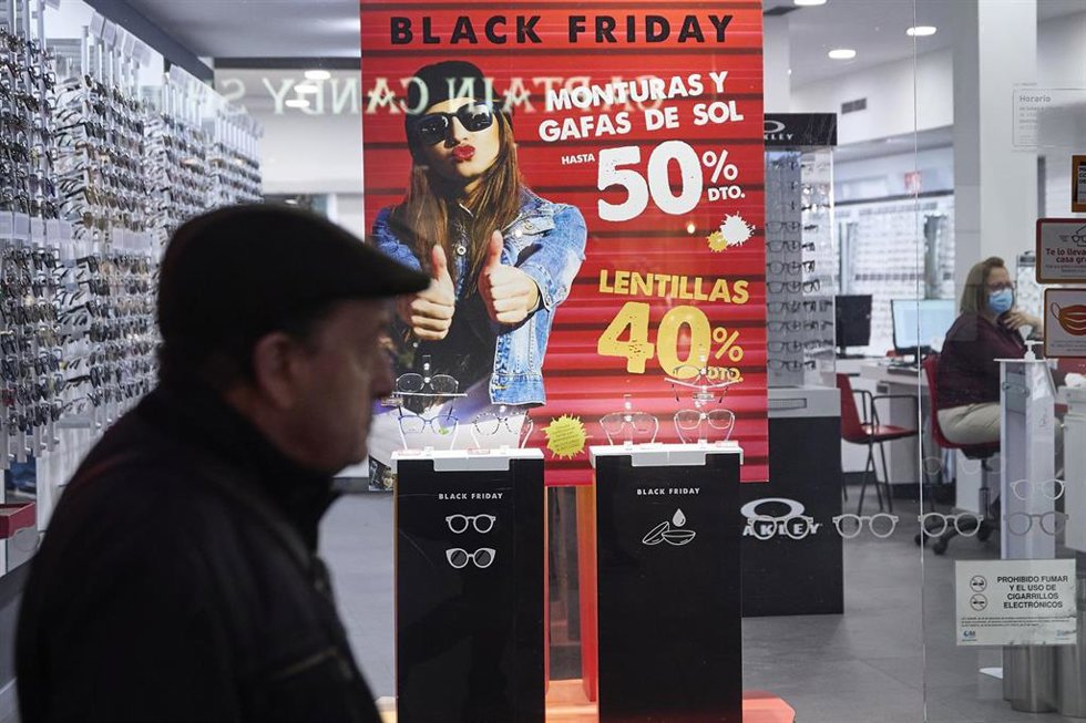 Varias personas pasan por delante de los comercios que anuncian los descuentos del Black Friday.