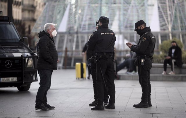 Archivo - Un hombre habla con varios policías nacionales en la Puerta del Sol, en Madrid (España), a 30 de diciembre de 2020. 