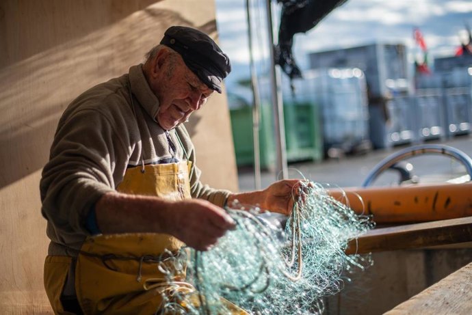 Archivo - Pescador rehaciendo una red