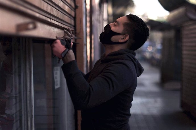 Archivo - Un hombre abre su tienda en Santiago de Chile 