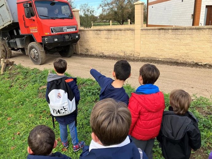 Un grupo de niños delante de un camión de obra
