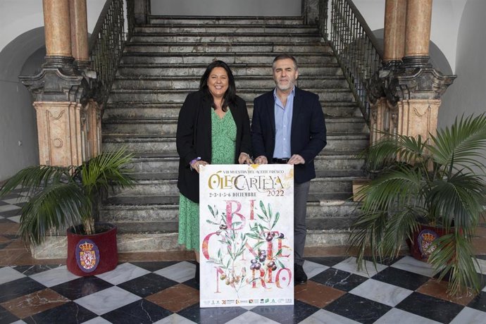 Dolres Amo y Vicente Tapia con el cartel de la VIII Muestra del Aceite Fresco 'Óleo Carteya 2022'.