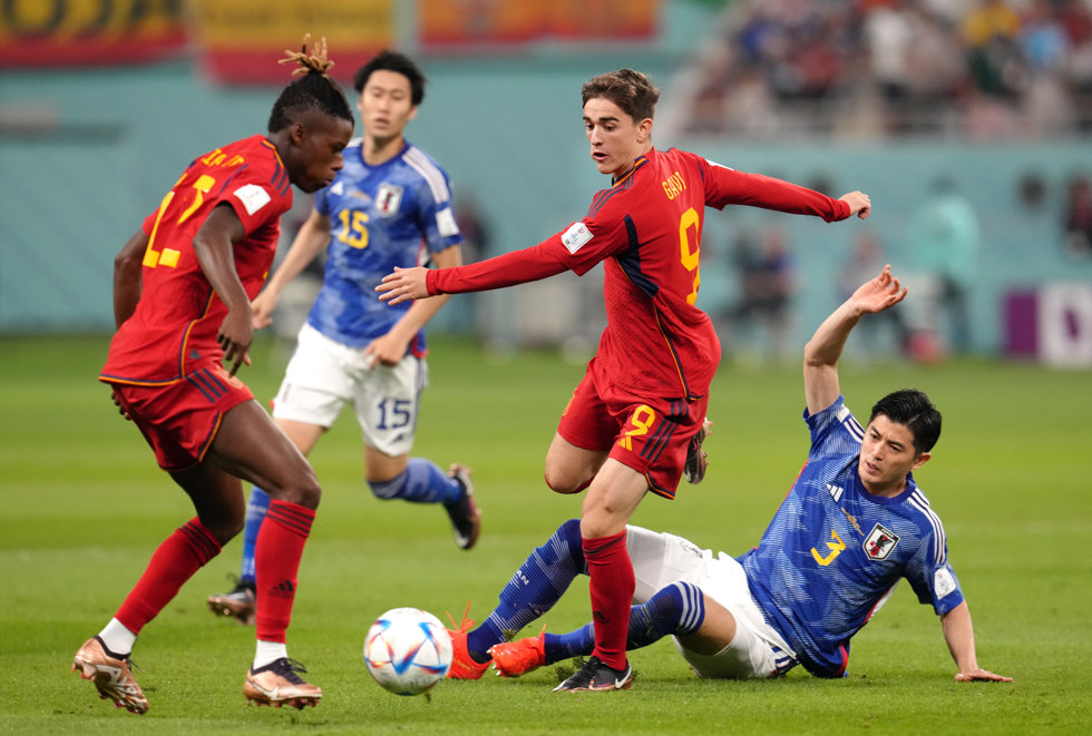 01 December 2022, Qatar, Al Rayyan: Spain's Gavi (C) is tackled by Japan's Shogo Taniguchi during the FIFA World Cup Qatar 2022 Group E soccer match between Japan and Spain at Khalifa International Stadium. Photo: Nick Potts/PA Wire/dpa
