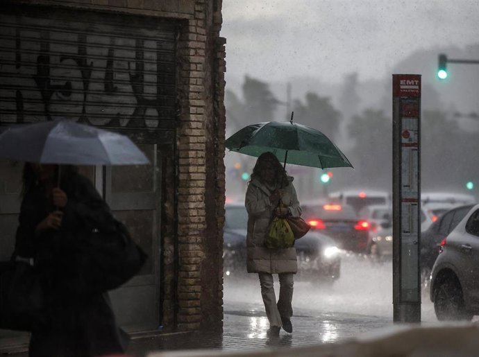 Dos mujeres caminan mientras se protegen de la lluvia con paraguas