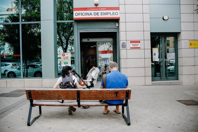 Archivo - Dos personas esperan fuera de una oficina de empleo