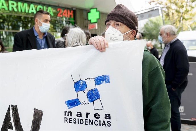 Archivo - Un hombre sostiene junto a más personas de la Marea de Residencias.