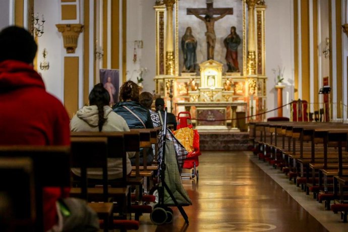 Archivo - Varias personas sentadas en los bancos de una Iglesia en Madrid.