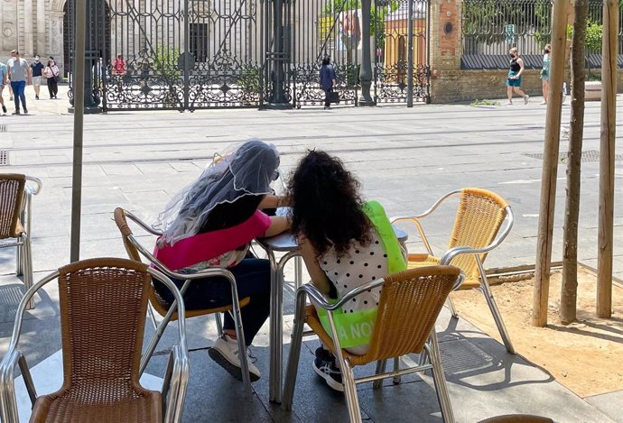 Archivo - Dos jóvenes, ataviadas con la vestimenta de las despedidas de soltera, en la terraza de un bar 