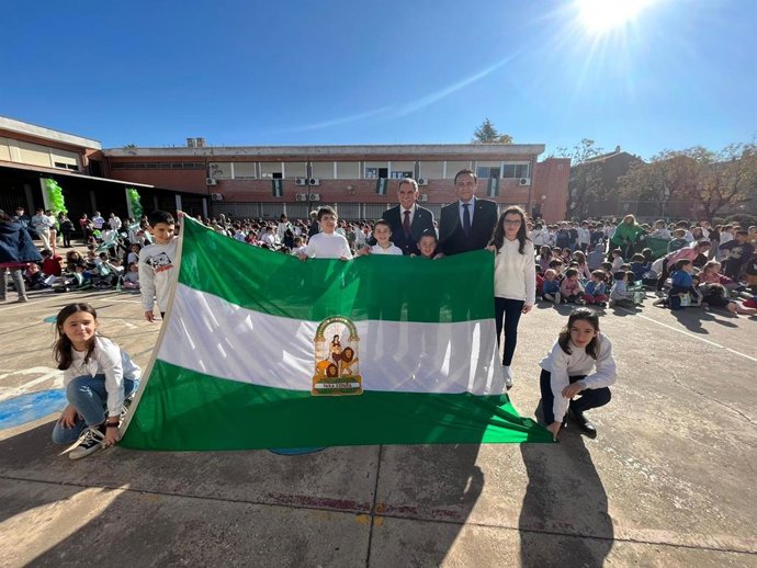 Gómez Villamandos (dcha.) y Viso, sostienen la bandera de Andalucía junto a alumnos del CEIP Pablo García Baena.
