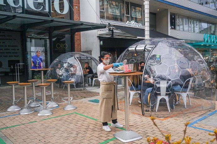 Archivo - 26 December 2020, Colombia, Bogota: A waitress serves food to customers who sit inside a capsule as a biosecurity measure due to the spread of coronavirus (COVID-19). Photo: Daniel Garzon Herazo/ZUMA Wire/dpa