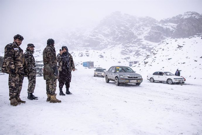 13 November 2022, Afghanistan, Salang Pass: Members of the Taliban stand guard as vehicles cross the Hindu Kush on the Salang Pass, the primary mountain pass connecting northern Afghanistan with Parwan Province, with onward connections to Kabul Province