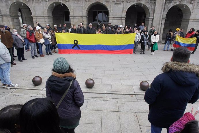 Varias personas portan una bandera de Colombia con un lazo negro durante una concentración convocada por la comunidad colombiana en Lugo para mostrar su repulsa por el asesinato de Cristina Cabo, en la Praza Maior de Lugo.