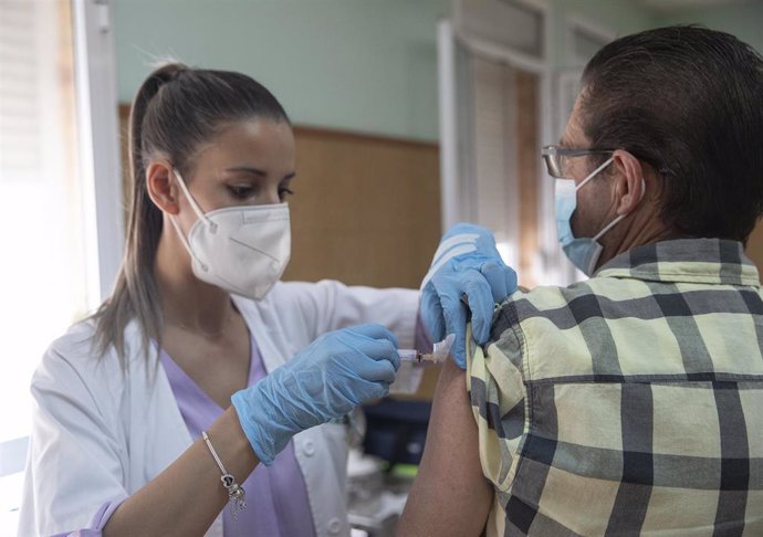 Archivo - Una enfermera vacuna a un hombre contra la gripe y el Covid.