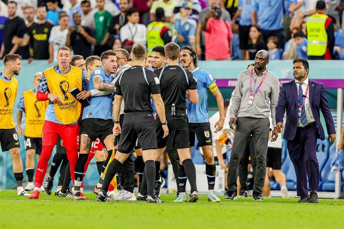 Giménez, Cavani y varios jugadores uruguayos rodean al trío arbitral tras el Uruguay-Ghana del Mundial de Catar