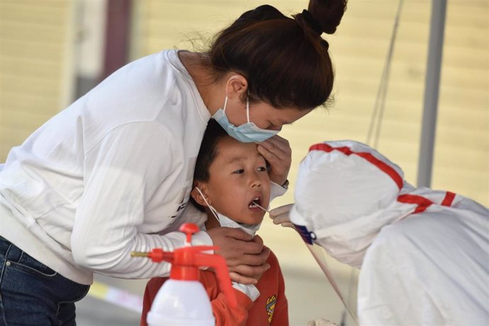 Archivo - Un trabajador sanitario recoge muestras  de COVID-19 de un niño, Fuyang, China