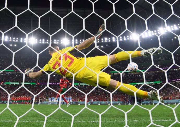 06 December 2022, Qatar, Al-Rayyan: Morocco's Hakim Ziyech scores his side's second penalty against Spain's goalkeeper Unai Simon during the penalty shoot-out of the FIFA World Cup Qatar 2022 Round of 16 soccer match between Morocco and Spain at the Edu