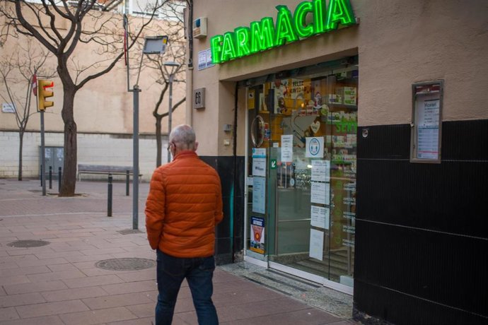 Archivo - Una persona pasa al lado de una farmacia