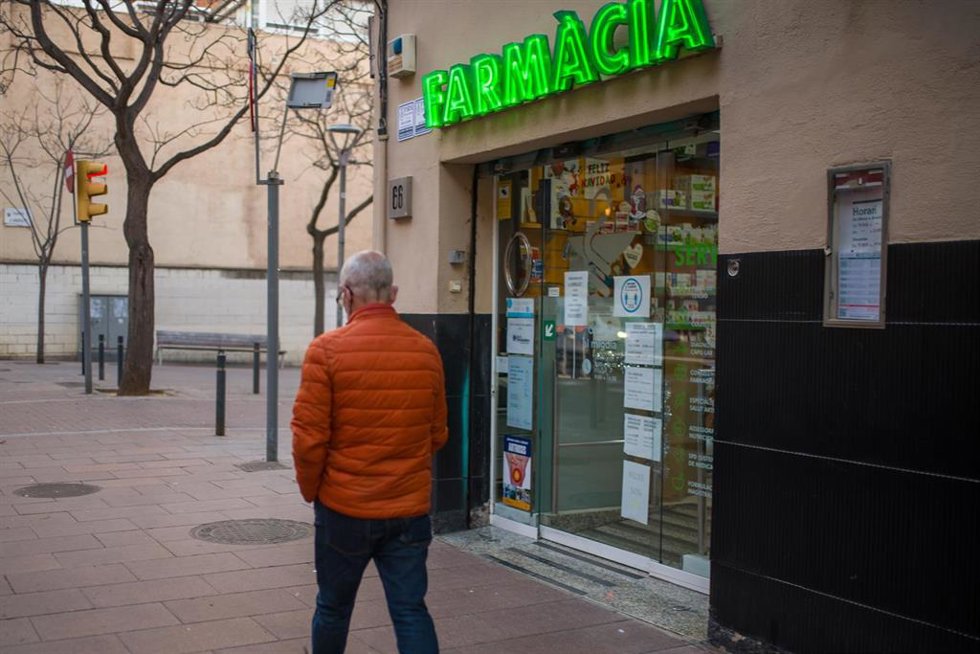 Archivo - Una persona pasa al lado de una farmacia