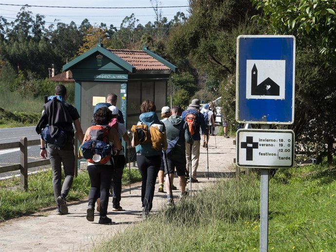 Archivo - Un grupo de peregrinos pasa frente a un cartel que indica el horario de misas mientras realizan el Camino de Santiago, en Santiago de Compostela, a 9 de octubre de 2021, en Santiago de Compostela, A Coruña, Galicia (España). Galicia amplía des