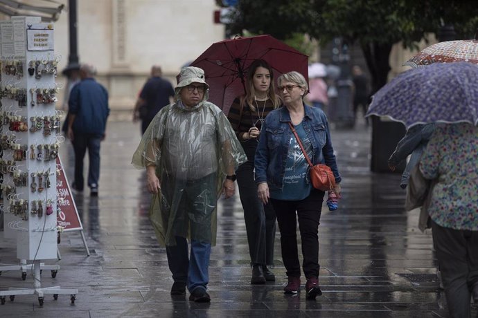 Archivo - Varias persona con impermeable y paraguas. A 21 de octubre de 2022, en Sevilla (Andalucía, España).