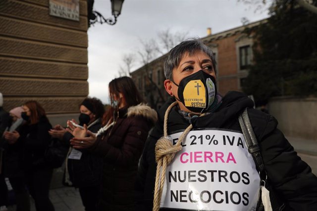 Archivo - Una mujer sostiene una pancarta mientras lleva una cuerda atada al cuello durante una protesta de profesionales de peluquería y estética, frente al Senado, a 9 de diciembre de 2021, en Madrid (España). Durante la protesta, trabajadores y trabaja