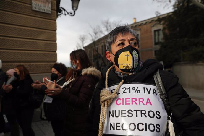 Archivo - Una mujer sostiene una pancarta mientras lleva una cuerda atada al cuello durante una protesta de profesionales de peluquería y estética, frente al Senado, a 9 de diciembre de 2021, en Madrid (España). Durante la protesta, trabajadores y traba