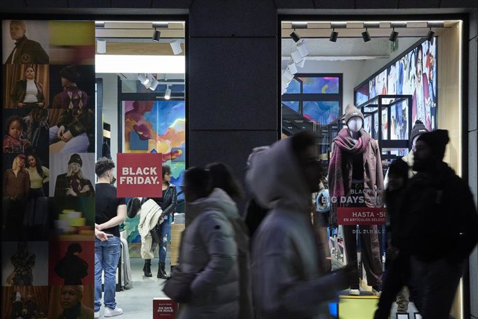 Varias personas pasan por delante de los comercios que anuncian los descuentos del Black Friday, 
